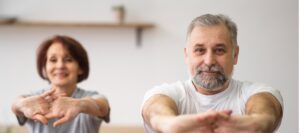 Starsza kobieta i starszy mężczyzna ćwiczą, żeby przeciwdziałać osteoporozie.