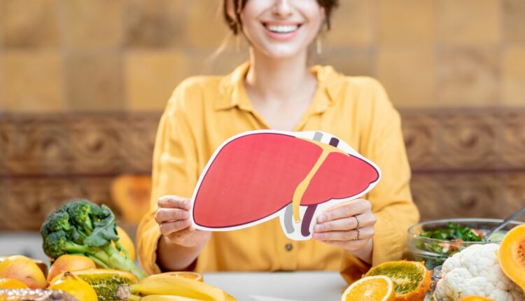 Uśmiechnięta kobieta trzyma w ręku rysunek wątroby. Wątroba a młodość